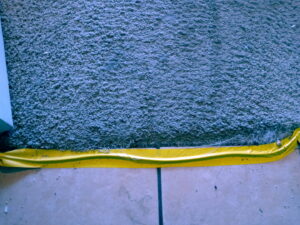 A carpet edge protected with yellow tape during work by Tucson Carpet Repair & Cleaning in Tucson, AZ.