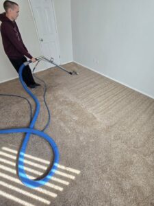 A technician performing carpet extraction cleaning, showing clean stripes on the carpet, for Carpet Care Express in Garland, TX