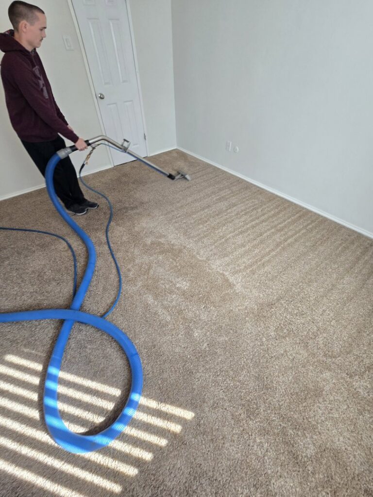 A technician performing carpet extraction cleaning, showing clean stripes on the carpet, for Carpet Care Express in Garland, TX