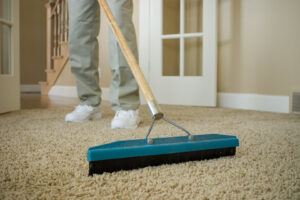 A person grooming a carpet with a specialized rake as part of the cleaning process by Champion Chem-Dry in Idaho Falls, ID.