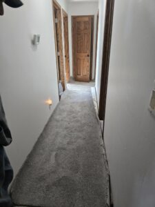 A hallway with new grey carpet being installed, showing the work in progress by Rosas Carpet & Flooring in Shorewood, IL.