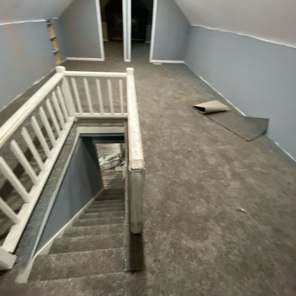 A hallway and staircase with new grey carpet installation, demonstrating work by HK Carpet Doctors in Sterling Heights, MI