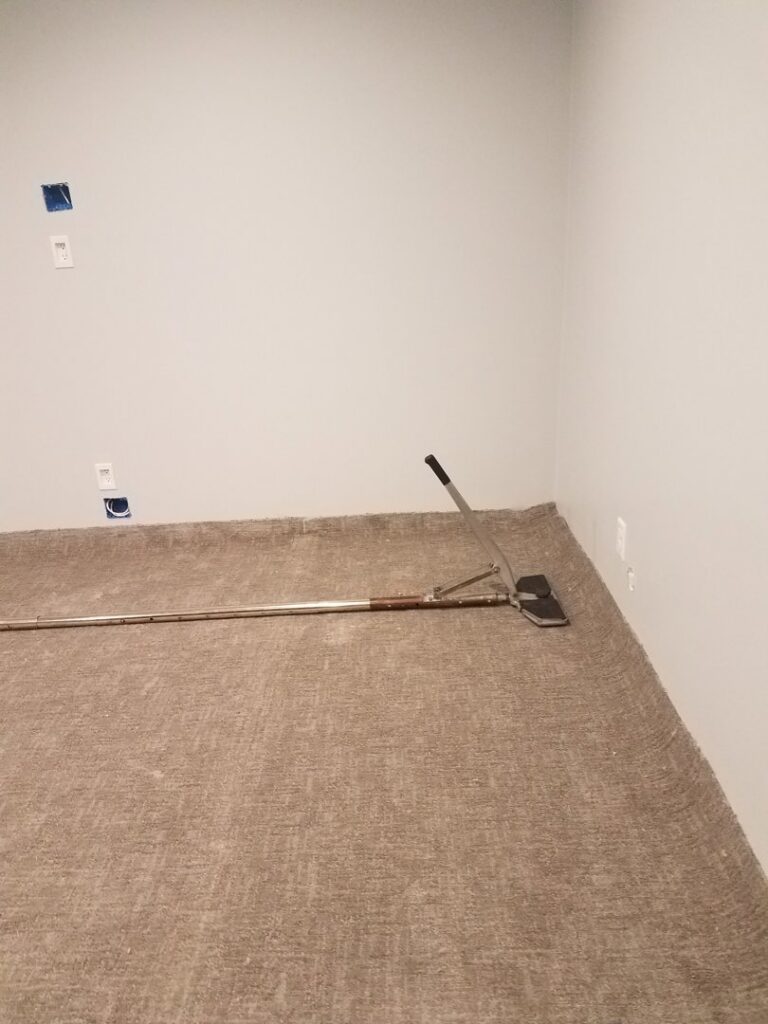 A carpet installation job in progress, showing a carpet stretcher tool used by Great Spaces Floor Co in Minneapolis, MN.