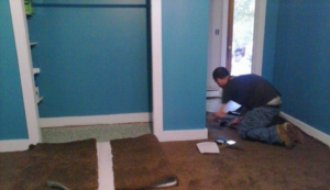 A professional installing new carpet in a room, showcasing the work of Knights Flooring in South Portland, ME.