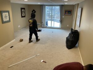 Two workers installing new carpet in a room, demonstrating a professional carpet contractor job by United Carpet in Rochester, NY.
