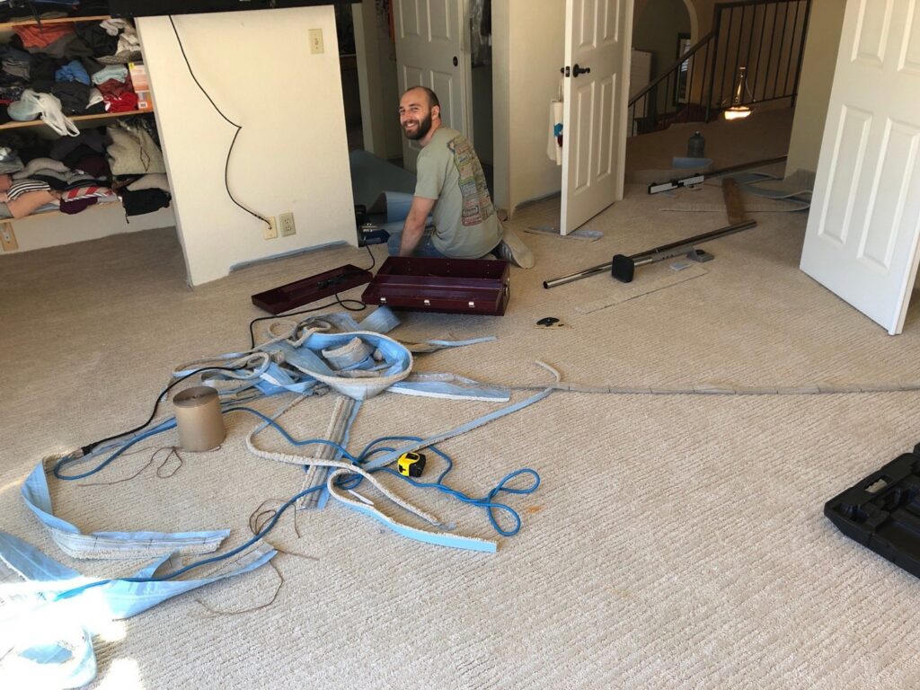 A skilled carpet contractor installing new carpet in a residential room, a service by Straus Carpets in Oakland, CA.
