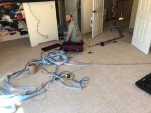 A skilled carpet contractor installing new carpet in a residential room, a service by Straus Carpets in Oakland, CA.