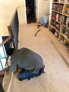 A professional carpet contractor installing new carpet on a staircase for Straus Carpets in Oakland, CA.