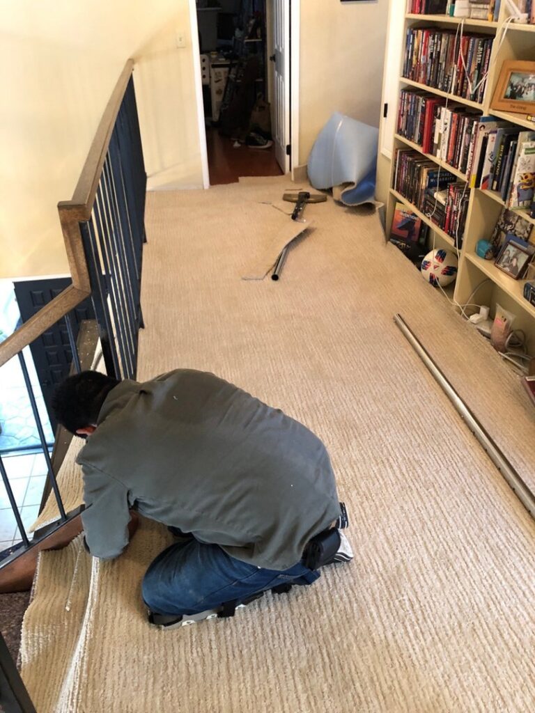 A professional carpet contractor installing new carpet on a staircase for Straus Carpets in Oakland, CA.