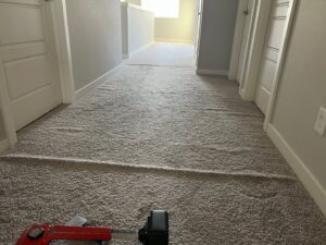 Carpet installation or stretching in progress in a hallway, with a carpet stretcher tool visible, by Mace Carpet Services in Tacoma, WA