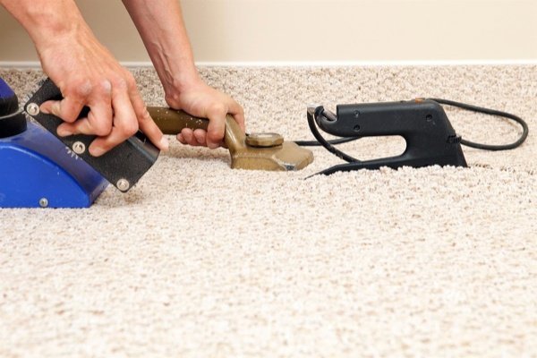 Hands using professional carpet installation tools for a carpet contractor job by Mid State Contract Cleaners in Nashville, TN.