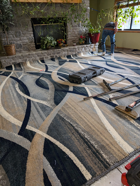 Carpet installation in progress, showing a power stretcher and tools by Craftmark Installations LLC in Broken Arrow, OK