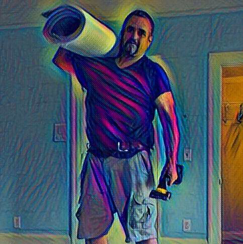 A carpet installer carrying a roll of carpet and a tool for Ed Massey Services in Roopville, GA.