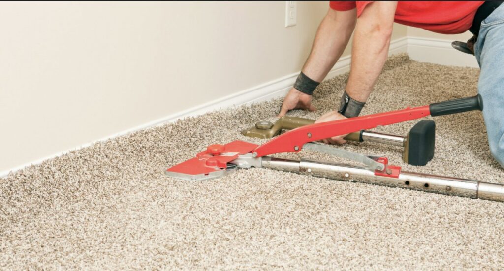 A carpet installer using a knee kicker and power stretcher to install carpet for Great Day Carpet & Tile Cleaning LLC Desoto in Olive Branch, MS.