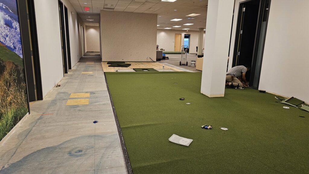 A carpet installer working on green artificial turf flooring at At Home Flooring in Naperville, IL.