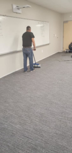 A carpet installer working on new carpet tile installation for Experience Carpet Installers in Dallas, TX.