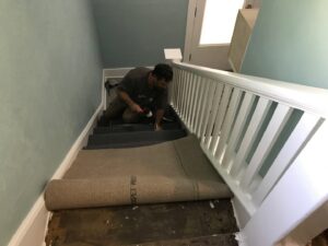 A carpet installer working on a staircase, demonstrating a carpet contractor job by Pierce Carpet Mill Outlet in Bozeman, MT.