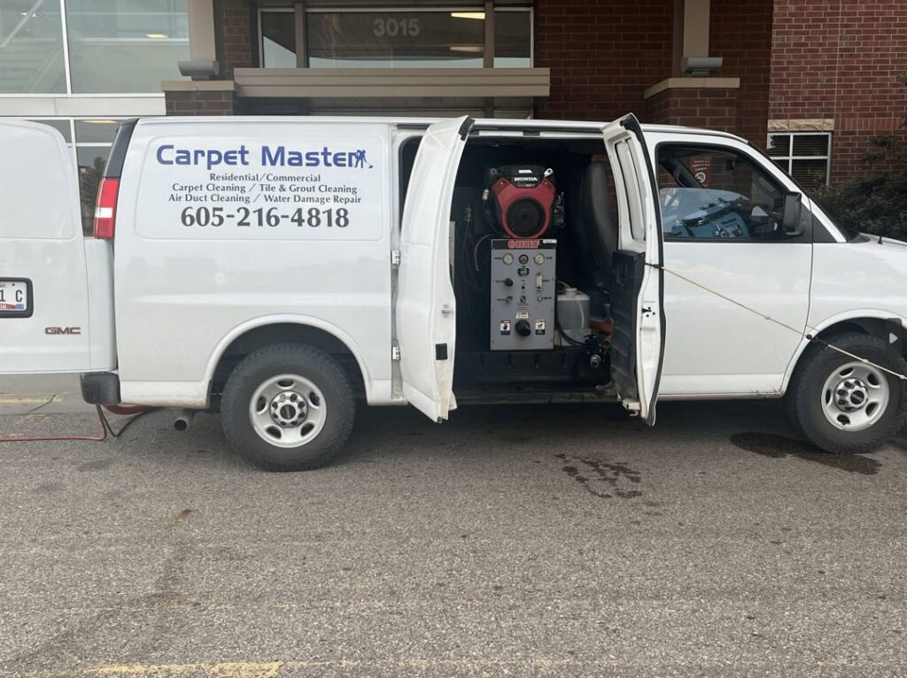 A Carpet Master service van with its side door open, revealing carpet cleaning equipment, parked in Aberdeen, SD.