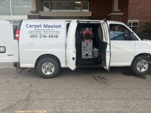 A Carpet Master service van with its side door open, revealing carpet cleaning equipment, parked in Aberdeen, SD.