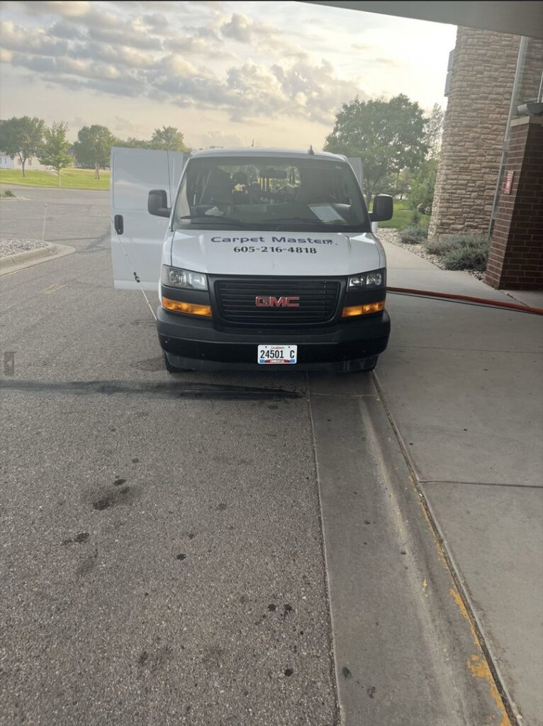 The front of a Carpet Master service van with hoses extended, indicating active carpet cleaning work in Aberdeen, SD.