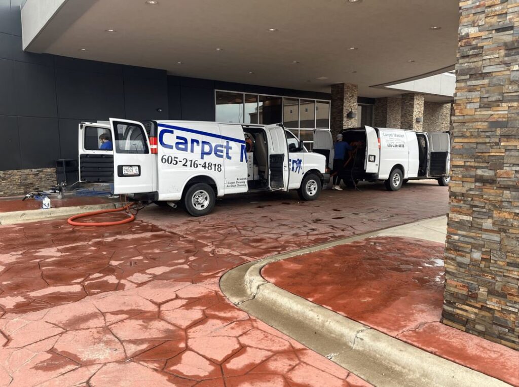 Two Carpet Master service vans parked outside a commercial building, ready for carpet cleaning services in Aberdeen, SD.