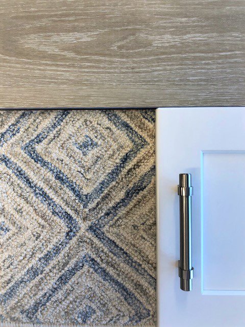 Close-up of a carpet sample alongside wood and cabinet materials for selection at Adda Carpet and Flooring in New Orleans, LA.