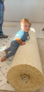 Carpet padding being installed on a floor by Carpet Mart Inc in Janesville, WI, showing a roll and laid sections.