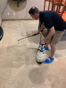 A technician from Heaven's Best Carpet Cleaning in Oklahoma City, OK, applying pre-treatment spray to a carpet.