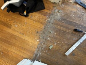 Debris and staples on a hardwood floor after carpet removal by Footprints Floors LA / San Fernando Valley in Studio City, CA.