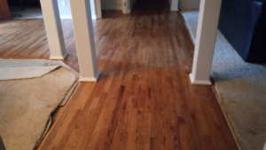 Carpet being removed from a hallway, revealing hardwood floors underneath, by Sterling Wood Floors in Medford, OR.