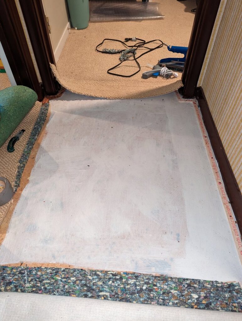 Carpet removed in a hallway, showing subfloor and padding, indicating carpet installation or removal by Dewdrop Carpet Cleaning in Kansas City, MO.