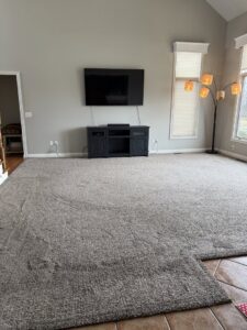 A large carpeted room with a section of carpet rolled back, indicating carpet work by Referral Cleaning and Restoration Inc. in Fort Wayne, IN.