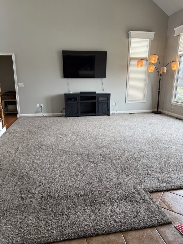 A large carpeted room with a section of carpet rolled back, indicating carpet work by Referral Cleaning and Restoration Inc. in Fort Wayne, IN.