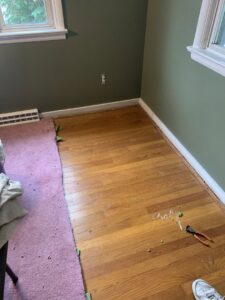 Pink carpet removal in progress, revealing wood floor by Sychterz Jeffrey G Standing & Refinishing Wood Floors, Reading, PA.