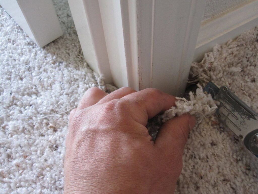 A hand performing carpet repair or installation work with a utility knife by Spectrum Cleaning & Restoration in Medford, OR