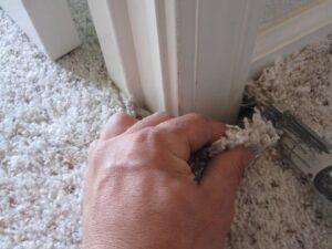 A hand performing carpet repair or installation work with a utility knife by Spectrum Cleaning & Restoration in Medford, OR