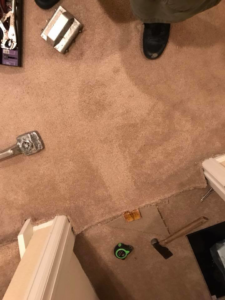 Carpet repair tools, including a stretcher and tape measure, laid out on a carpet by Brett's Pro Carpet Repair in Fort Collins, CO.