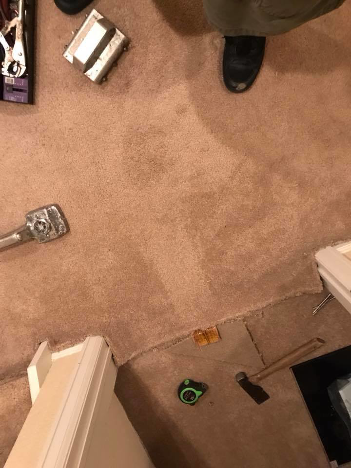 Carpet repair tools, including a stretcher and tape measure, laid out on a carpet by Brett's Pro Carpet Repair in Fort Collins, CO.