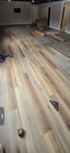 New gray carpet being installed with rolls visible by Flooring World Wide LLC in Plainwell, MI.