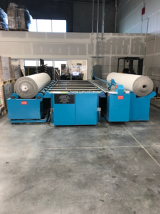 Large rolls of carpet being prepared on a cutting machine at Taylor Carpets in Lehi, UT.