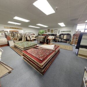 Rolls of carpet and stacked rugs in the Custom Crafted Floors showroom in Phoenix, AZ.