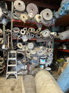 Large rolls of carpet and flooring materials stored in the warehouse of Delgado Carpet Services in San Jose, CA