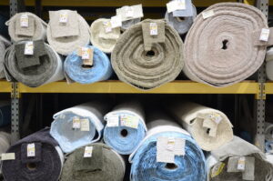 Numerous rolls of carpet in various colors and textures stored on racks in the warehouse of Gator Carpet and Tile in Jacksonville, FL.