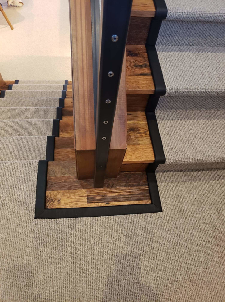 Detailed view of a custom carpet runner installation at the base of a staircase by Altered Edge in Kalispell, MT