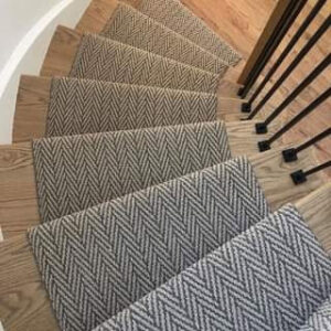 A stylish carpet runner with a herringbone pattern installed on wooden stairs by Sy's Discount Carpets in Los Angeles, CA