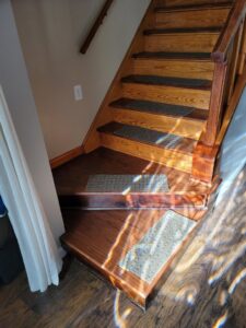 Carpet runners installed on a wooden staircase by Modern Flooring & Renovations WNY in Tonawanda, NY.