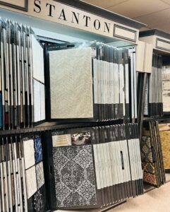 Rows of carpet samples on display racks in the showroom of All Surfaces Wholesale in Houston, TX.