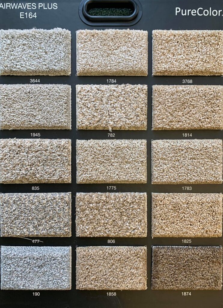 A display board showcasing various shades and textures of "Airwaves Plus" carpet samples from PureColor, available at Rojas Carpet and Flooring in Denver, CO.