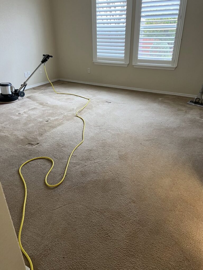 A professional carpet scrubber machine with a yellow power cord in a carpeted room, ready for cleaning by Steam Solutions Carpet Cleaning in San Antonio, TX.