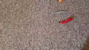 Close-up of a carpet seam with tools, indicating carpet repair or installation services by All Seasons Carpet Cleaning in Loves Park, IL.